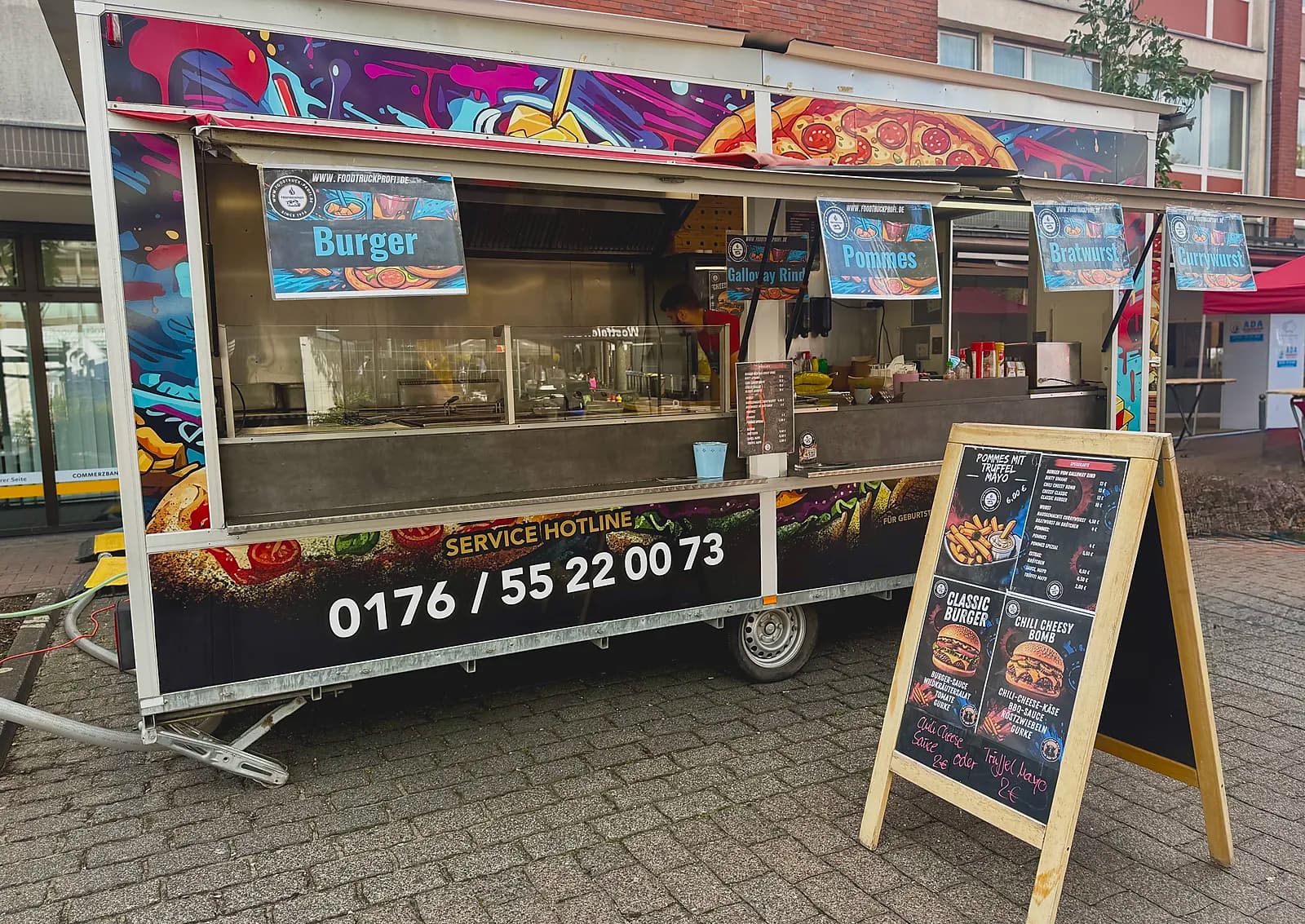 Foodtruck Außenansicht mit Speisekarte und Team bei der Zubereitung